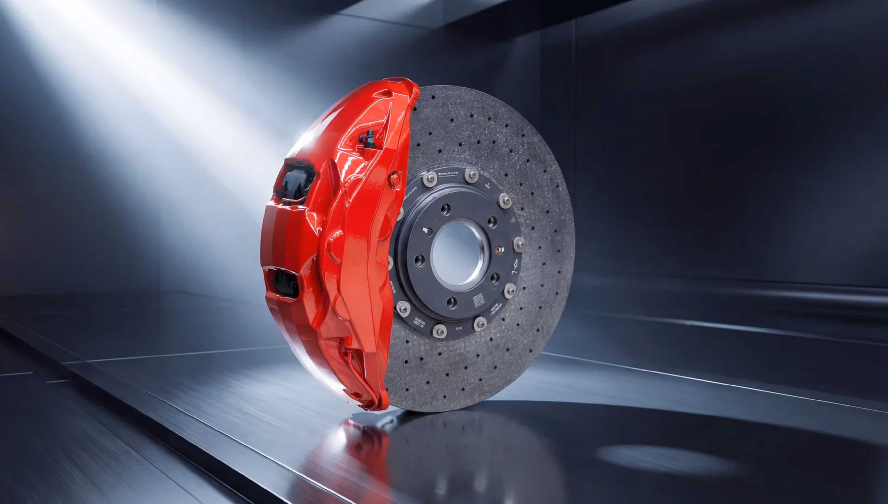 Red high-performance brake caliper attached to a perforated carbon brake disc.
