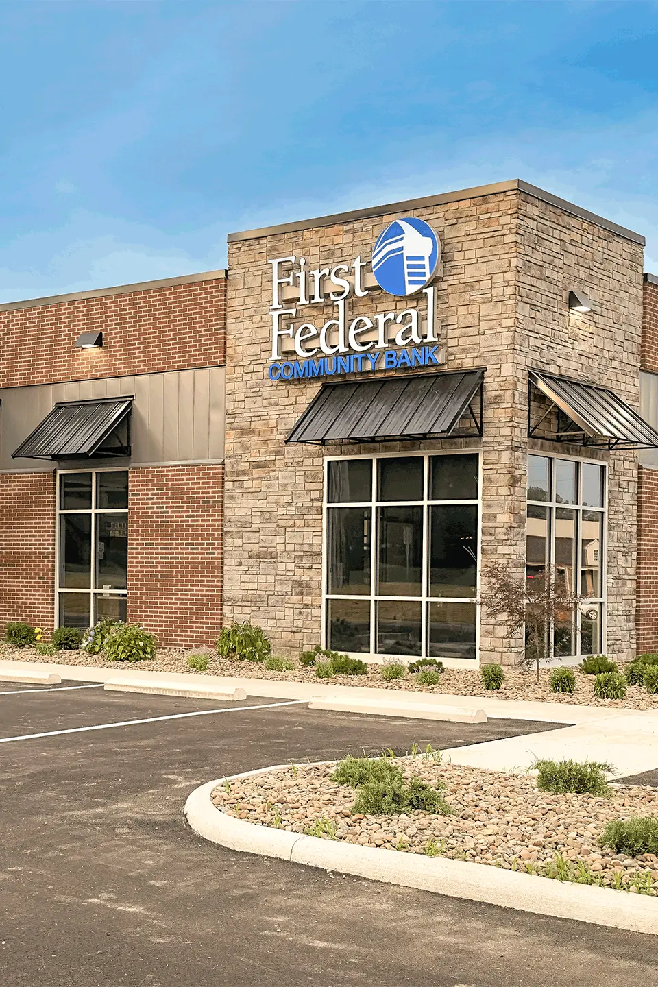 First Federal Community Bank building with brick and stone exterior under a clear blue sky.
