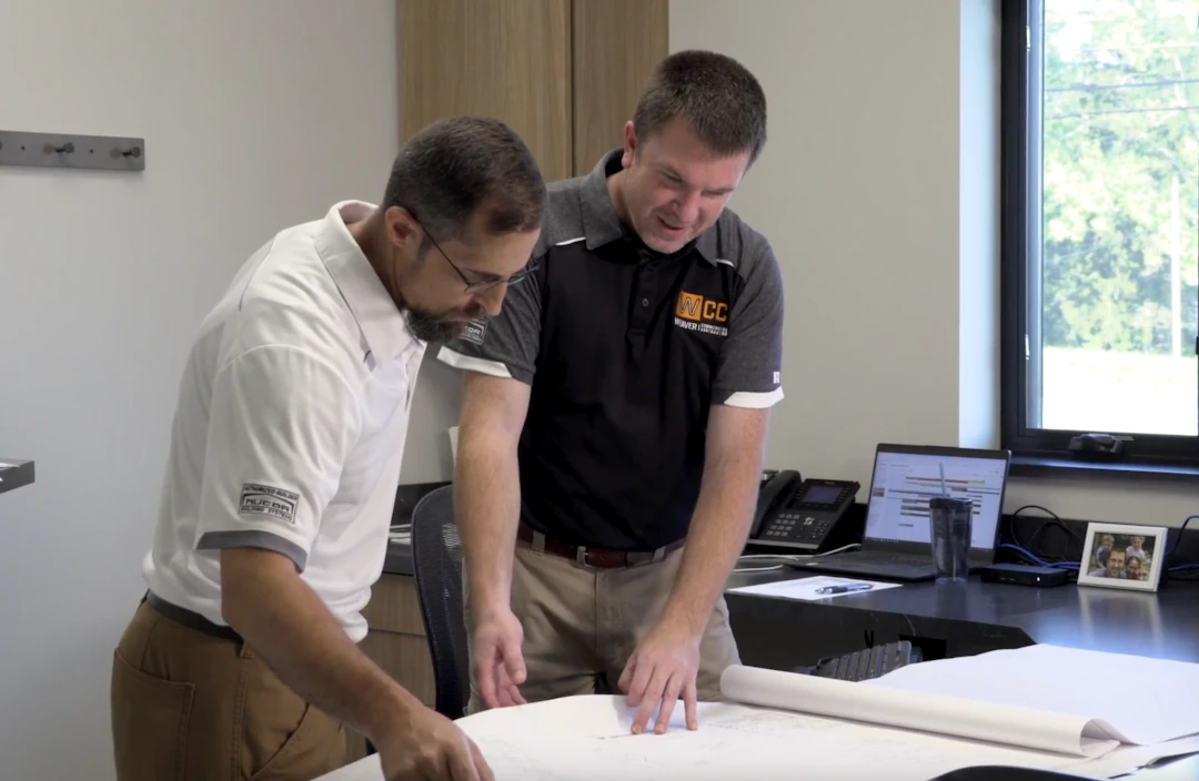 two men looking at building blueprints and documents