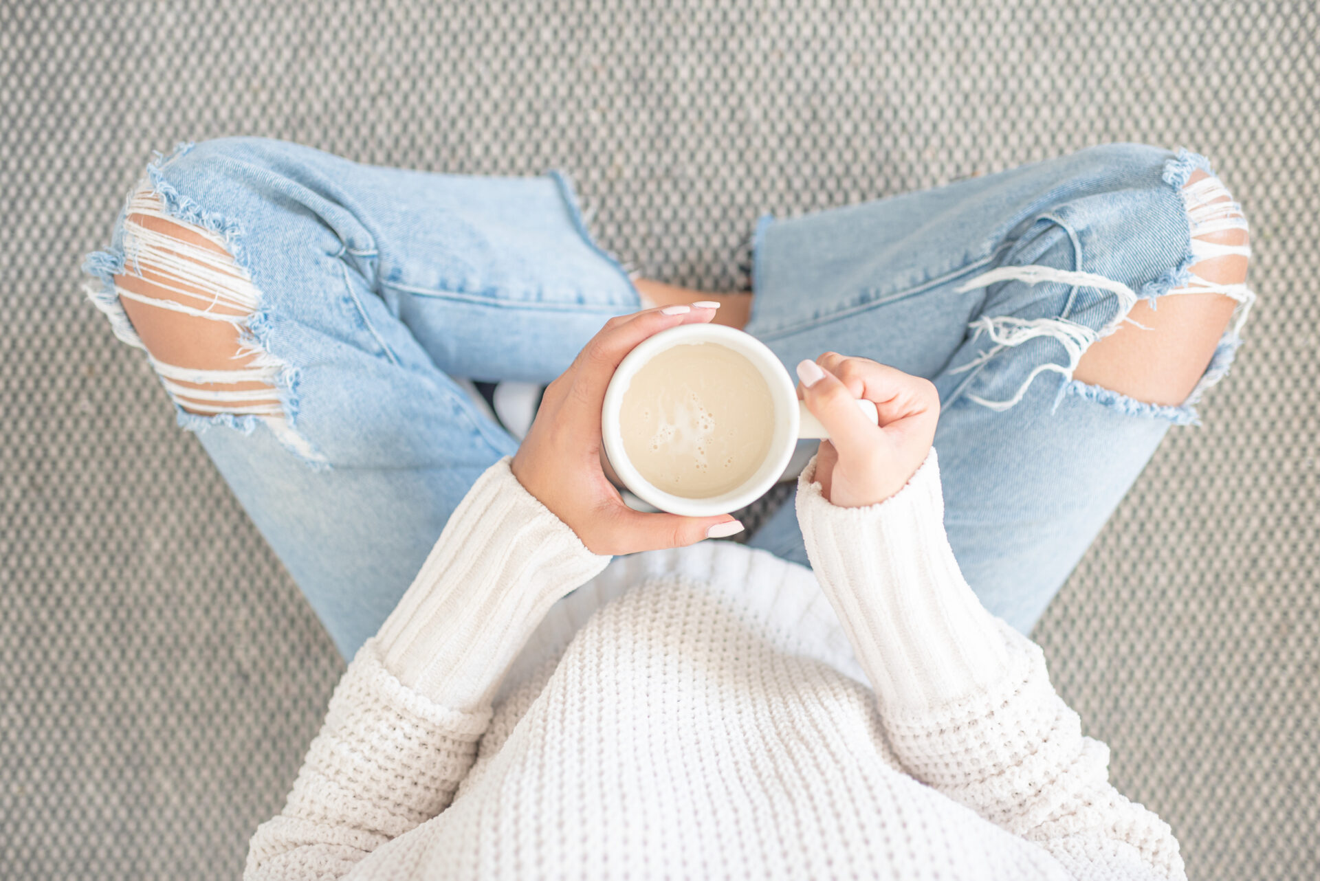 woman sitting cross legged on the floor holding a cup