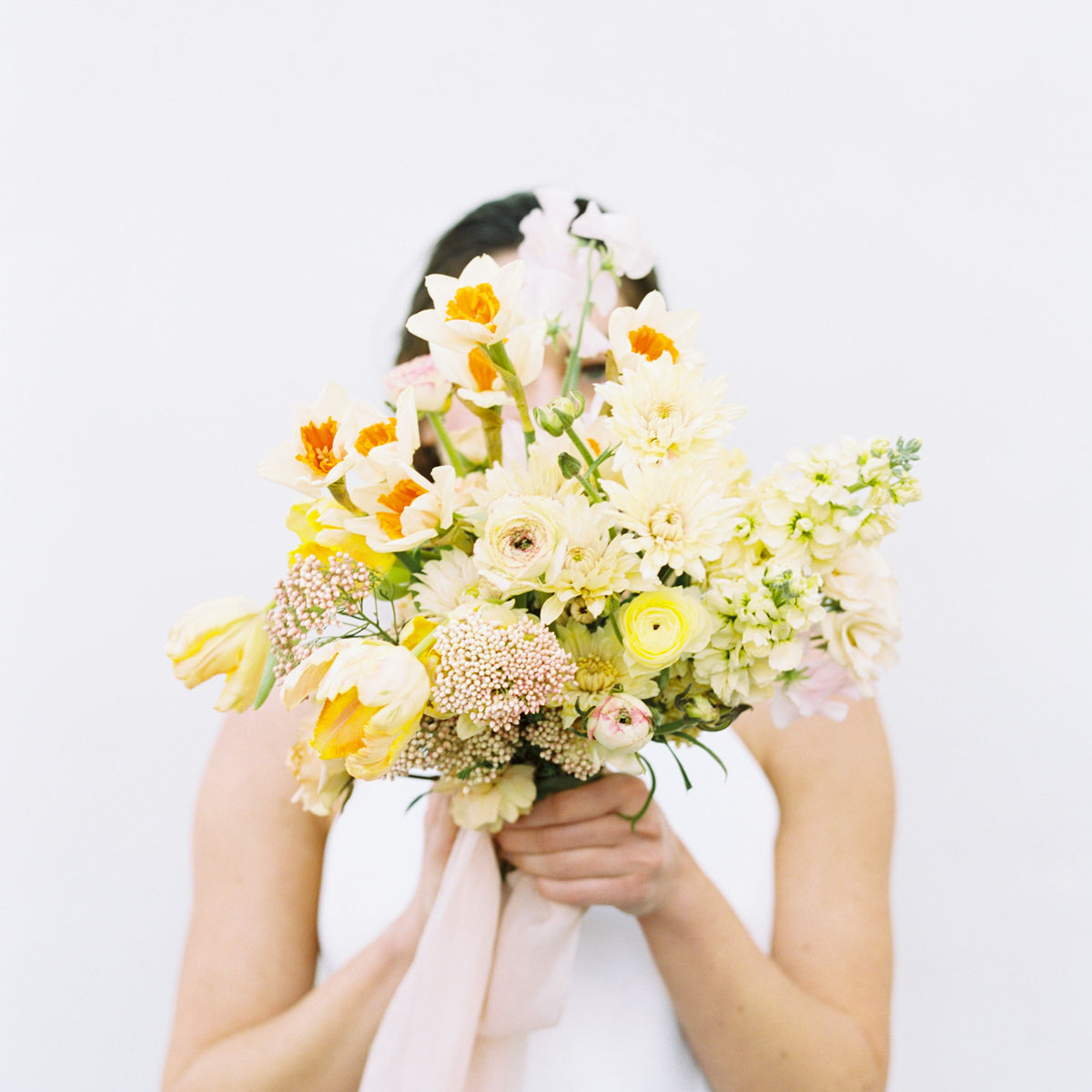 woman holding flowers that are hiding her face