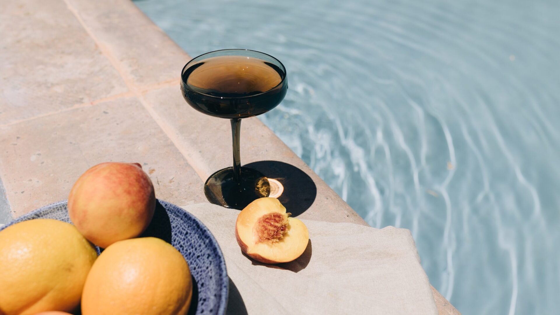 cup and oranges placed near a pool