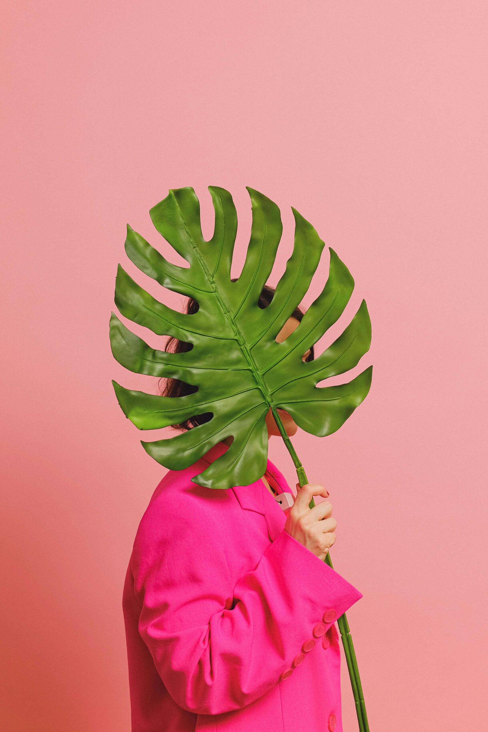 woman holding a huge plant to hide her face