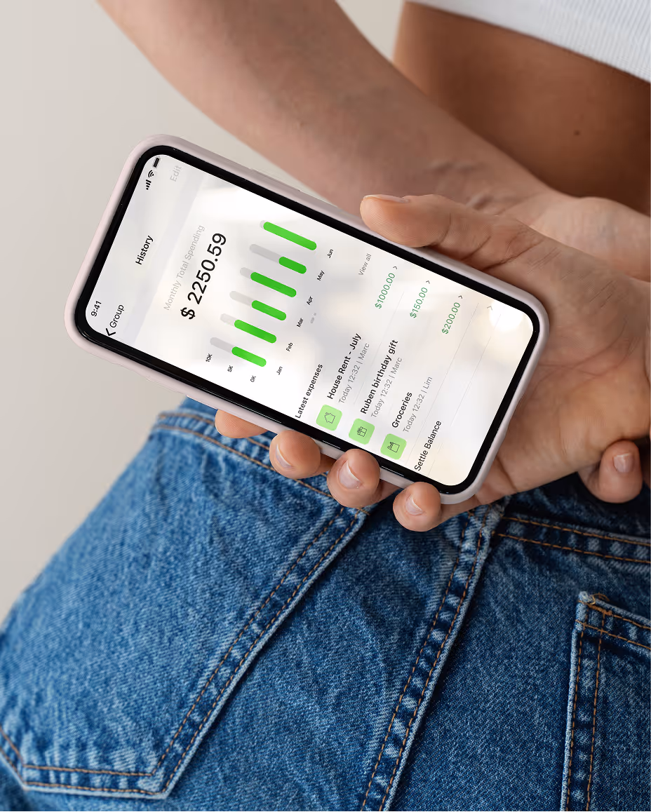 Hand holding smartphone displaying a spending app dashboard with monthly total spending of $2250.59 and latest expenses including house rent, birthday gift, and groceries.