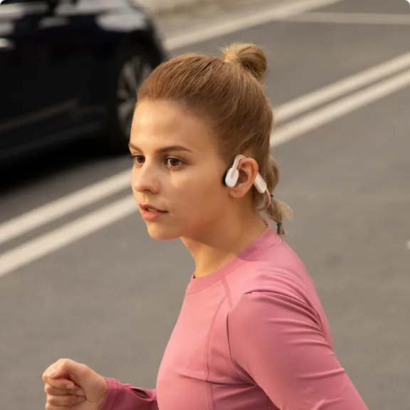 A woman jogging in the street wearing bone-conduction headphones