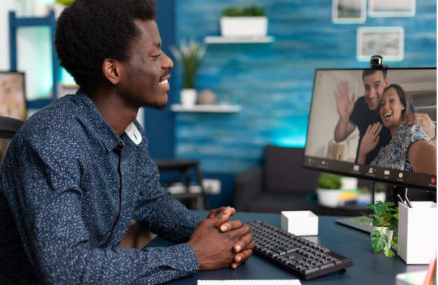 Black person smiling while on a video call with two people.