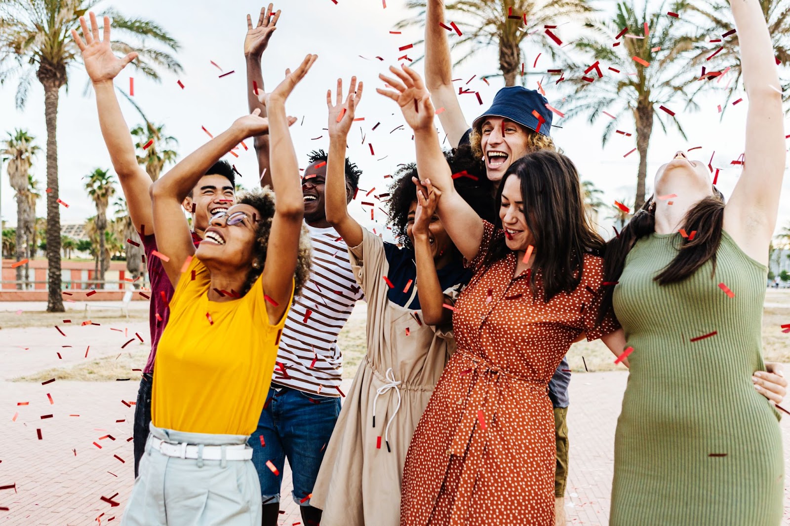 A group of young friends are outside throwing confetti.