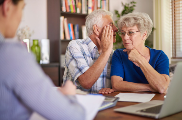 Man whispering to his wife ear in a doctor's office.