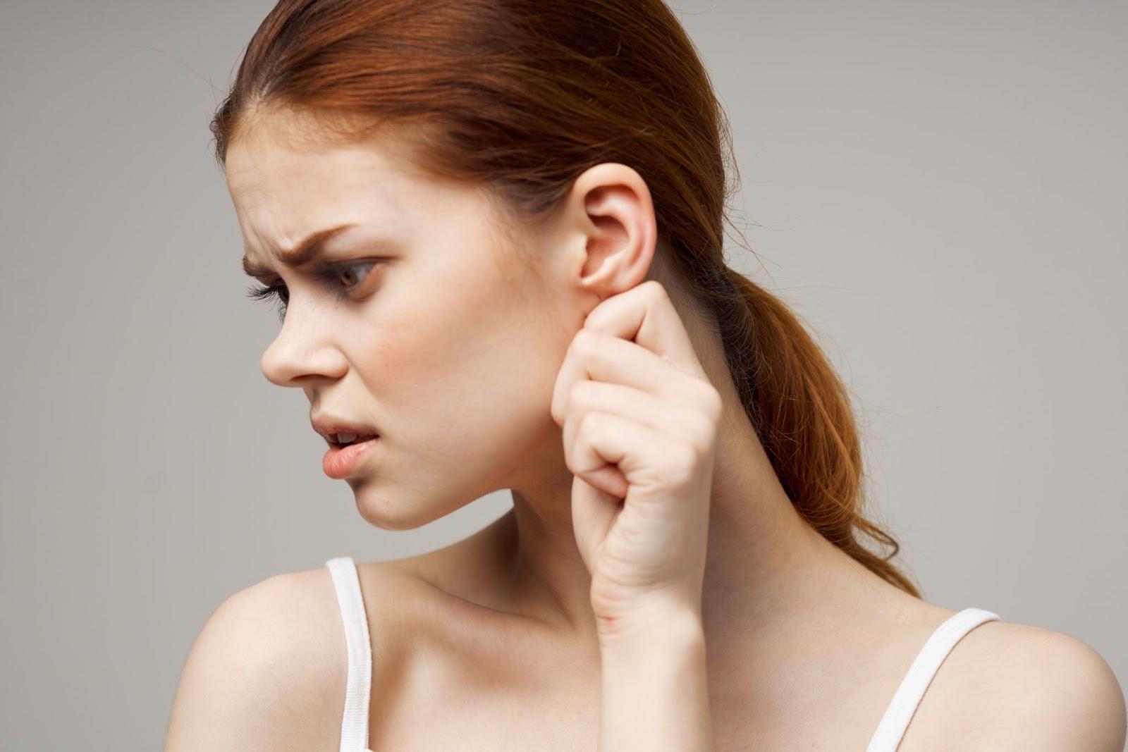 A woman gently tugs her earlobe.