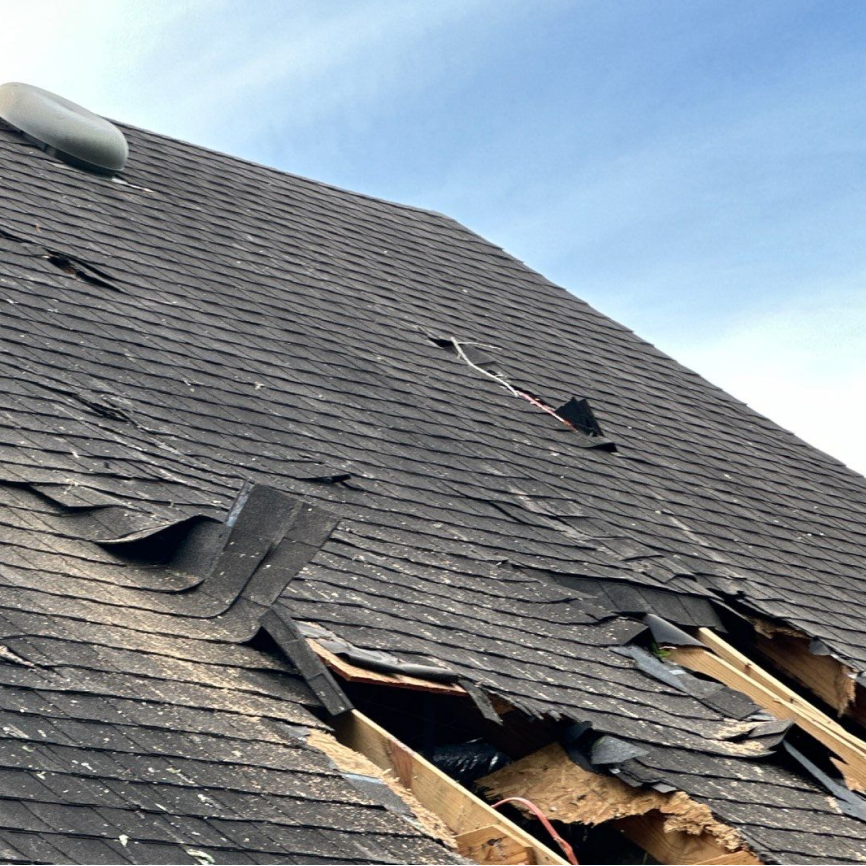 Sloped residential roof with visible hail damage marks on shingles