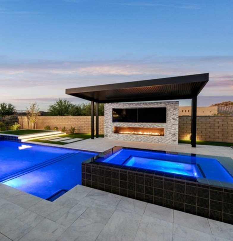 Pool with raised spa and covered ramada with linear fireplace at dusk by Kevens Landscape