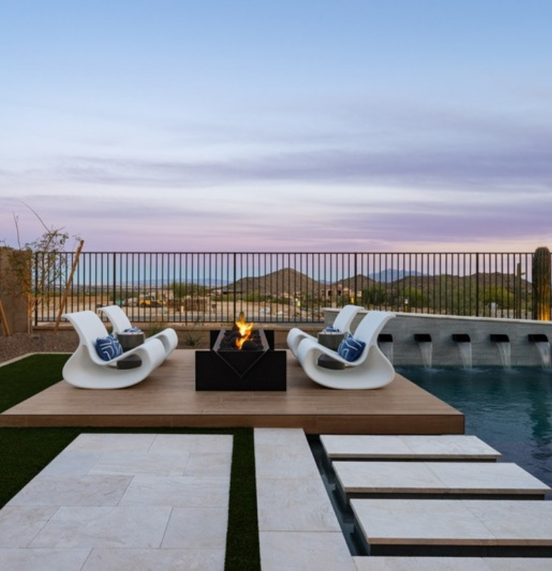 Fire pit lounge and pool with water spouts and mountain views at sunset by Kevens Landscape