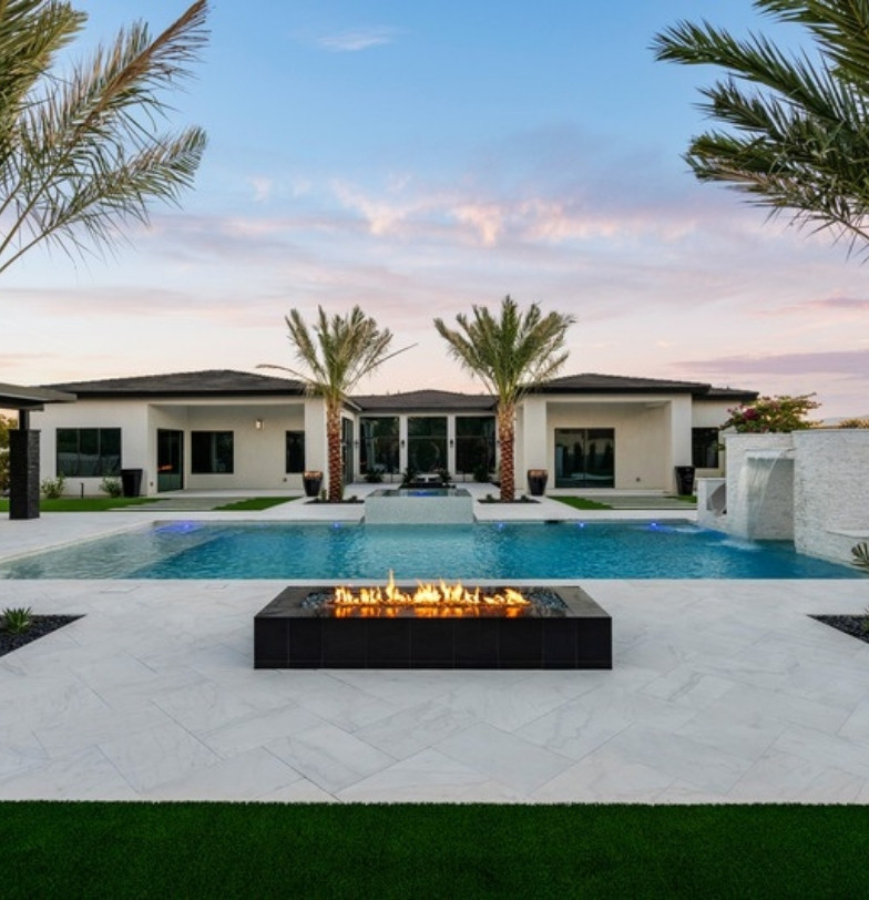 Estate backyard with pool, palms, fire feature and artificial turf at sunset by Kevens Landscape