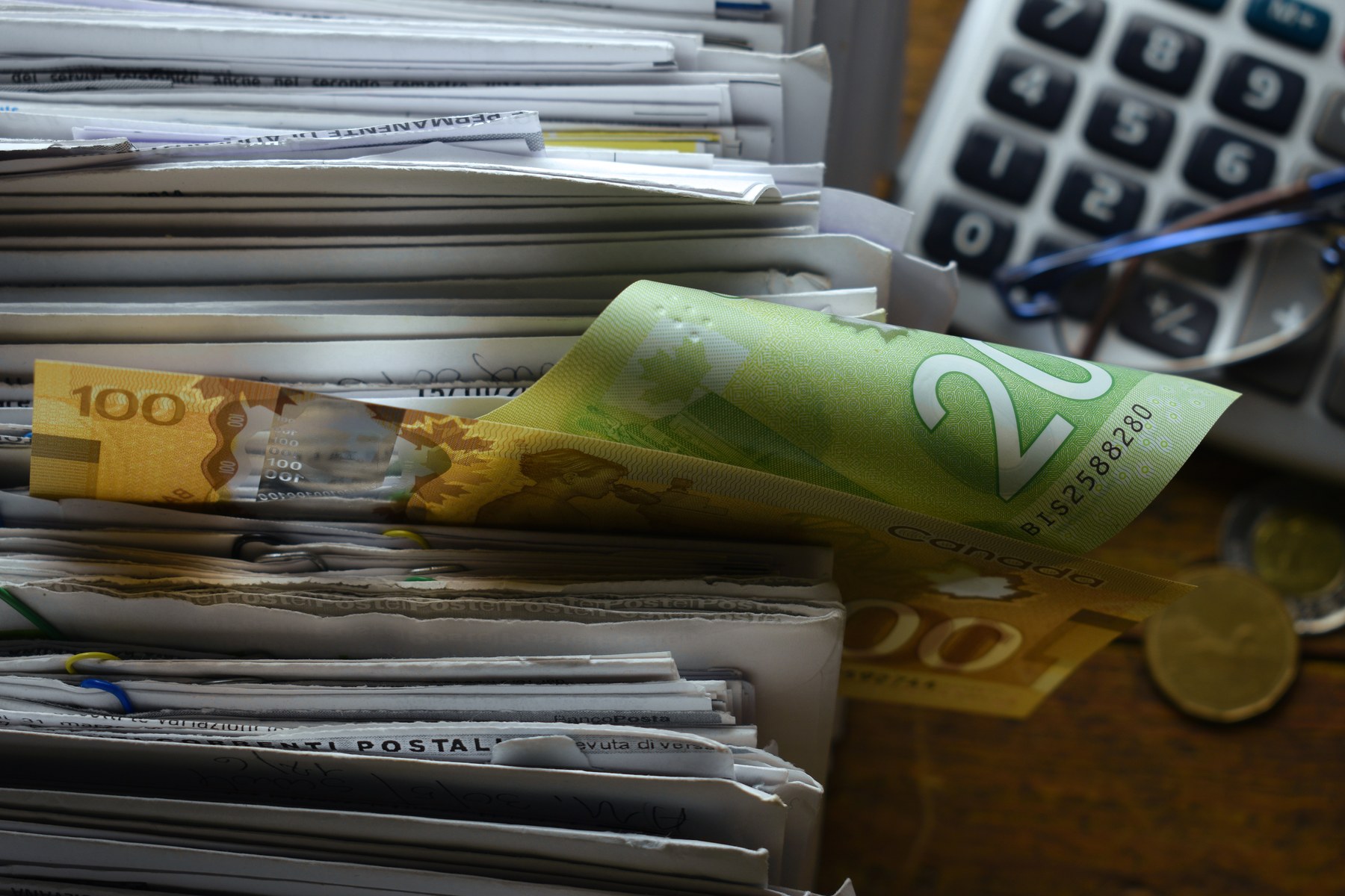 A stack of mail and envelopes with Canadian cash sticking out of them.