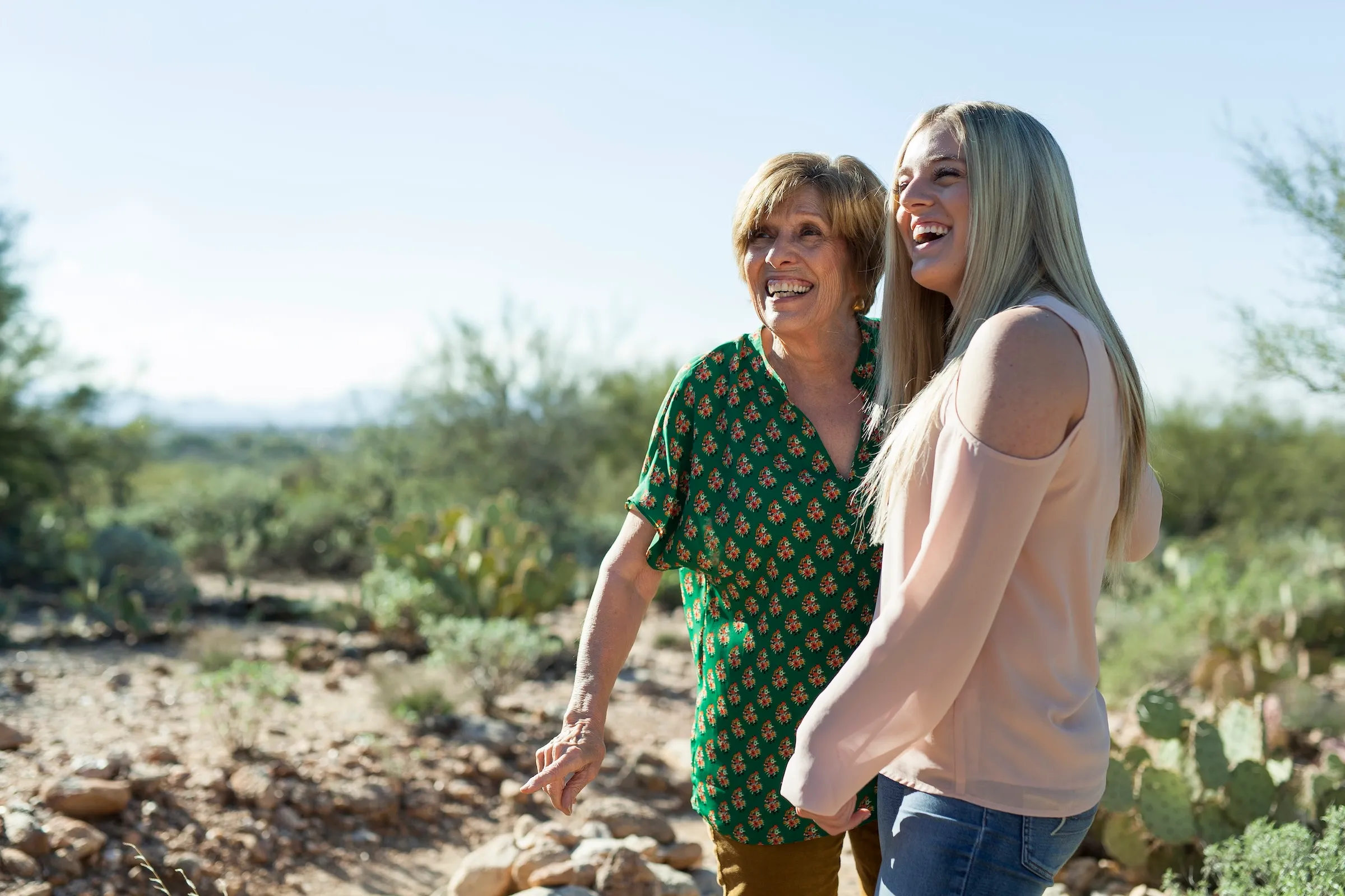 Two women smiling together in a desert landscape