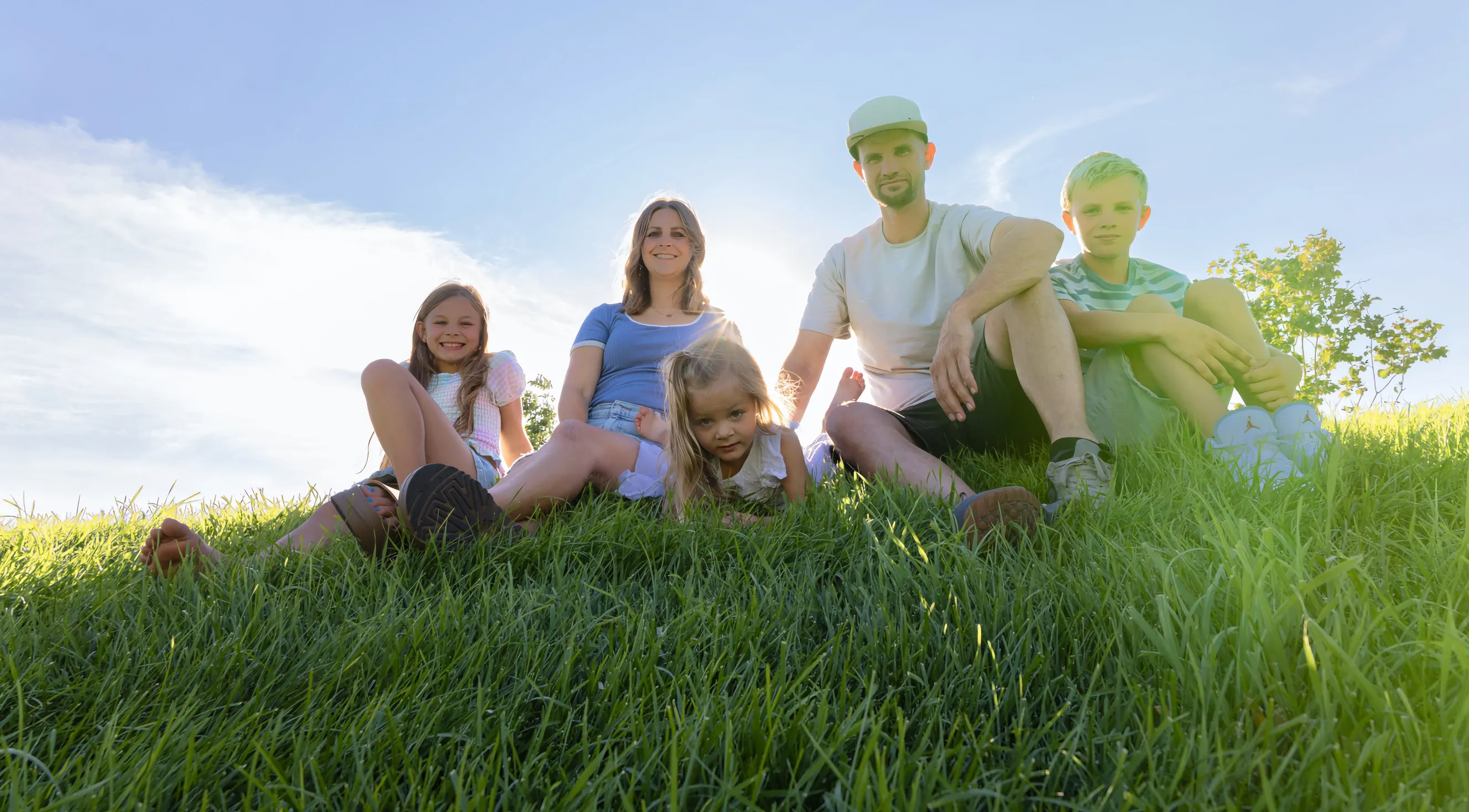 Family of five seated together in a grassy field