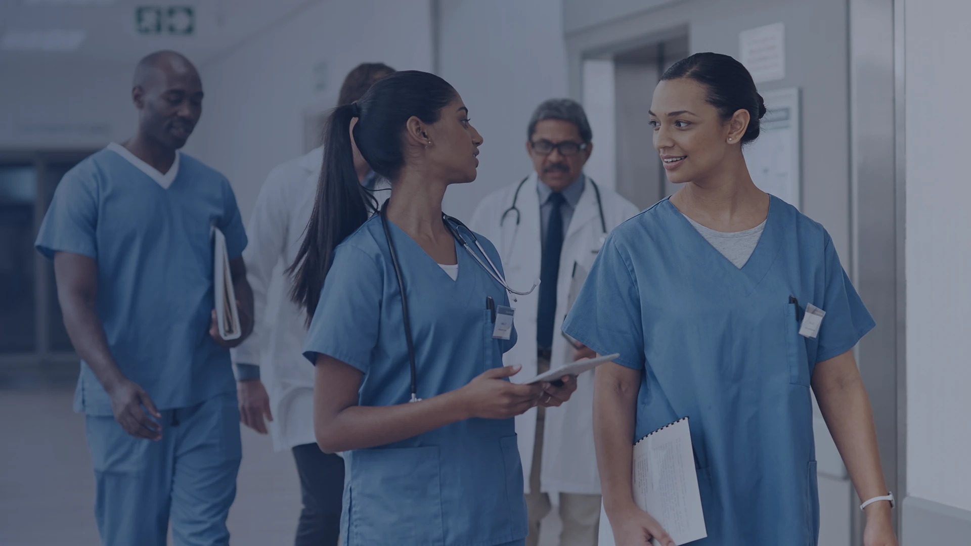 Nursing students walking in a hospital hallway while discussing their studies.