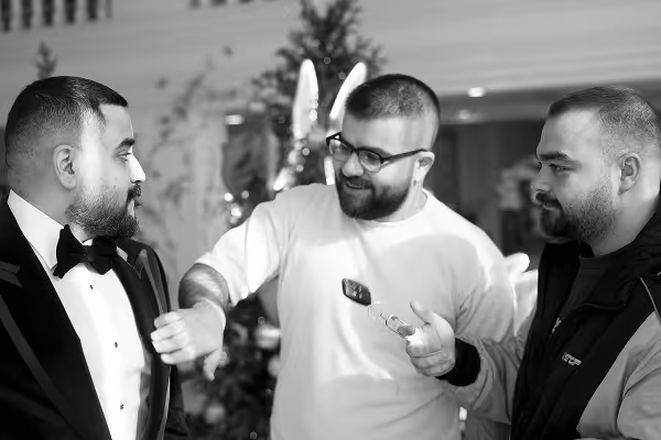 black and white image of a group of 3 people conversing (one in black tie and the other 2 are more casual)
