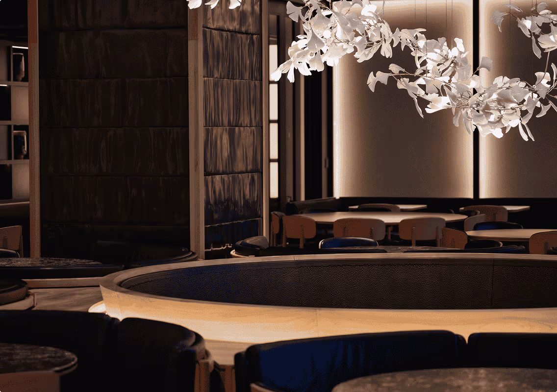 Dimly lit modern restaurant interior with a round booth, tables, chairs, and hanging white leaf decor.