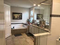 Modern Sacramento bathroom with a large bathtub, double sink vanity with cluttered countertop, tile flooring, and glass shower enclosure.