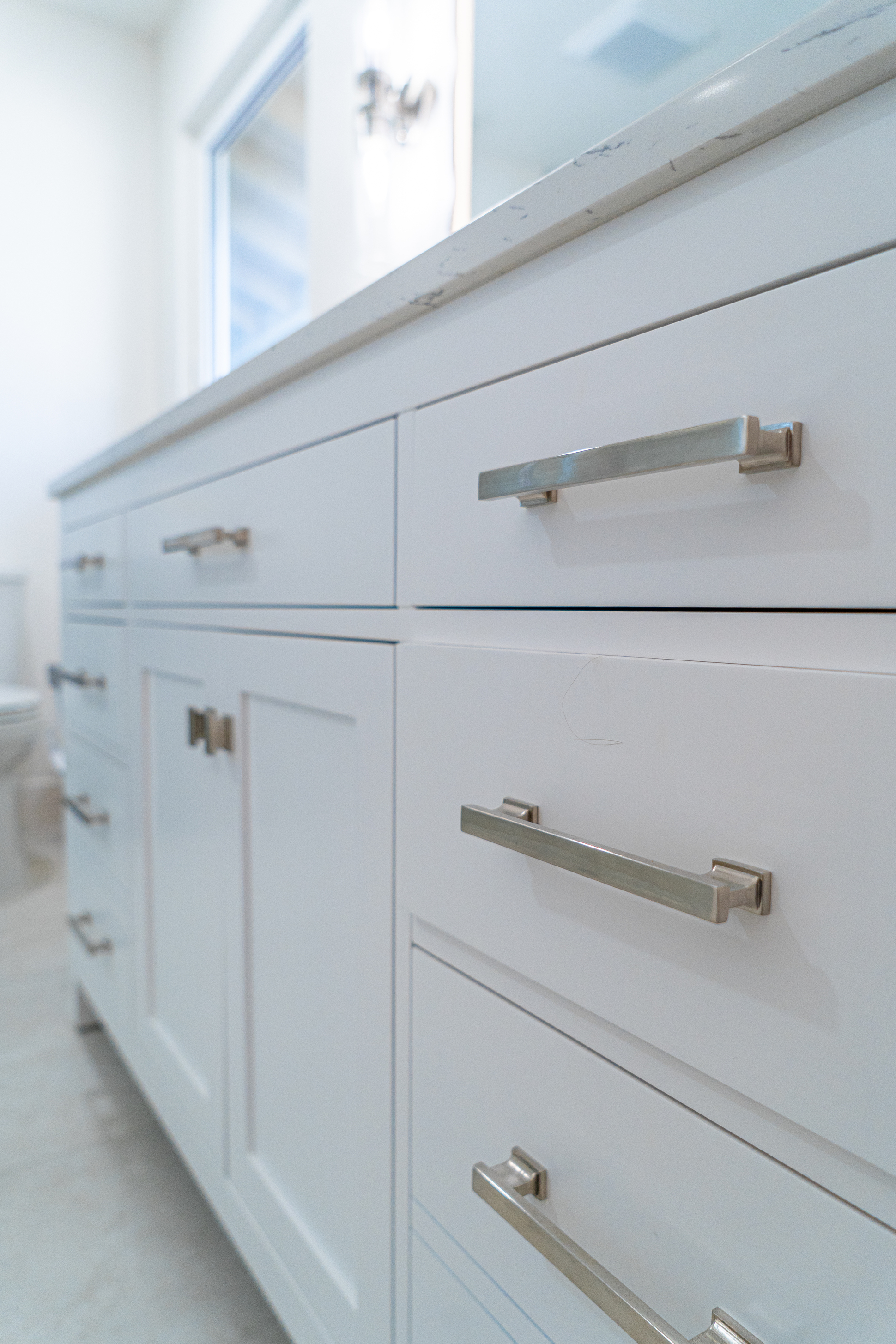 A close-up grayscale image of a geometric tile backsplash and hanging utensils.