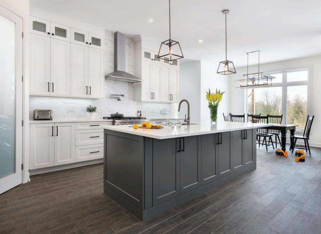 A grayscale photo showing white kitchen cabinets and a dining chair.