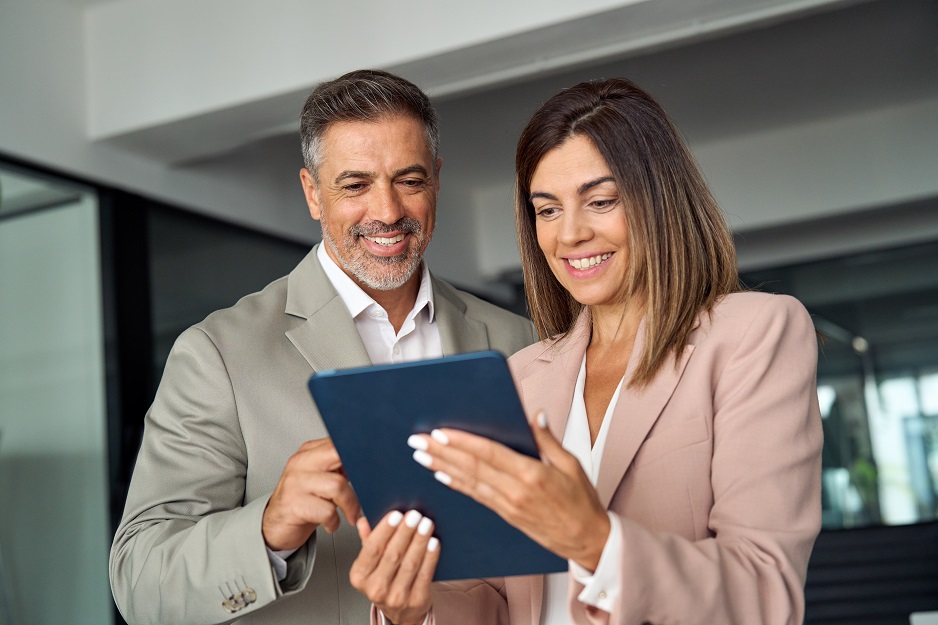 Smiling businesswoman and businessman looking at a digital tablet together in an office.