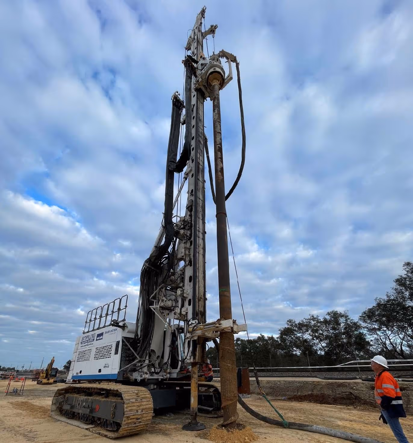 Grayscale group portrait of construction workers standing in front of heavy machinery.