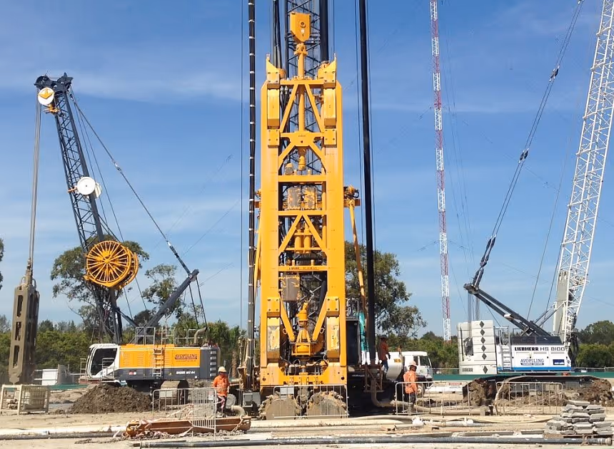 Grayscale group portrait of construction workers standing in front of heavy machinery.