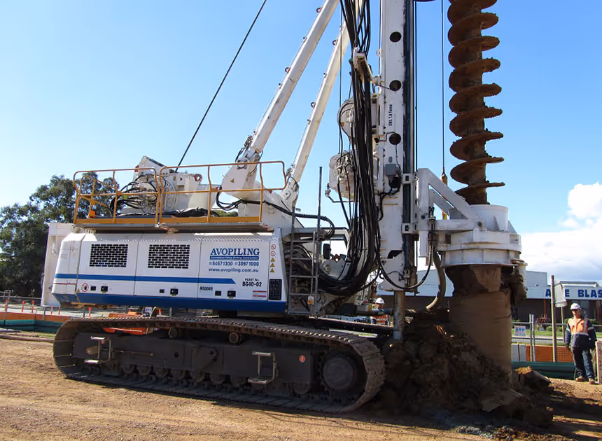 Grayscale group portrait of construction workers standing in front of heavy machinery.