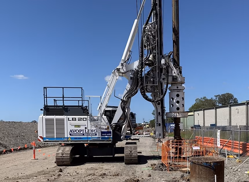 Grayscale group portrait of construction workers standing in front of heavy machinery.