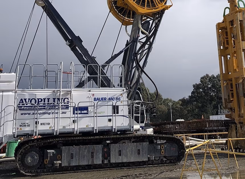 Grayscale group portrait of construction workers standing in front of heavy machinery.