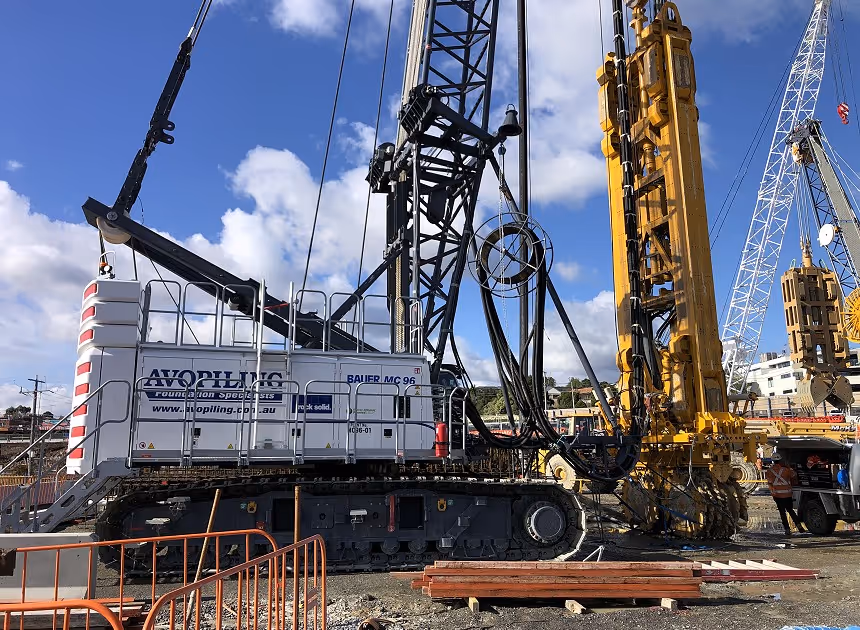 Grayscale group portrait of construction workers standing in front of heavy machinery.