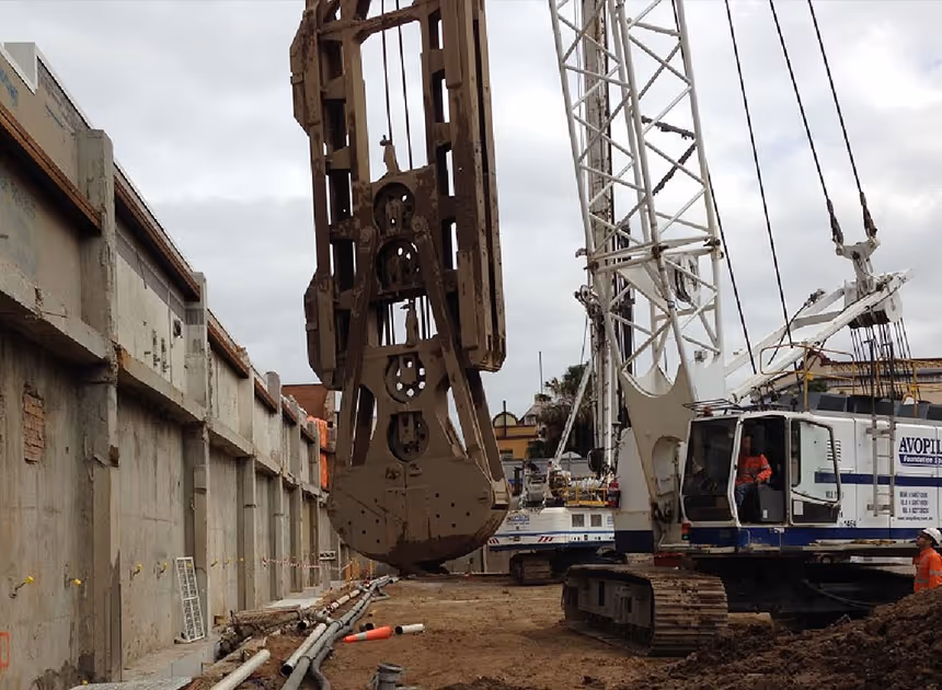 Grayscale group portrait of construction workers standing in front of heavy machinery.