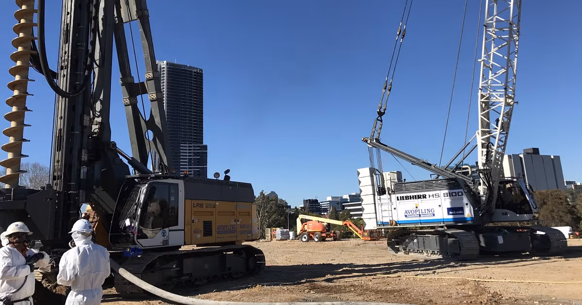 Grayscale aerial view of a large-scale urban construction site with multiple drilling rigs.