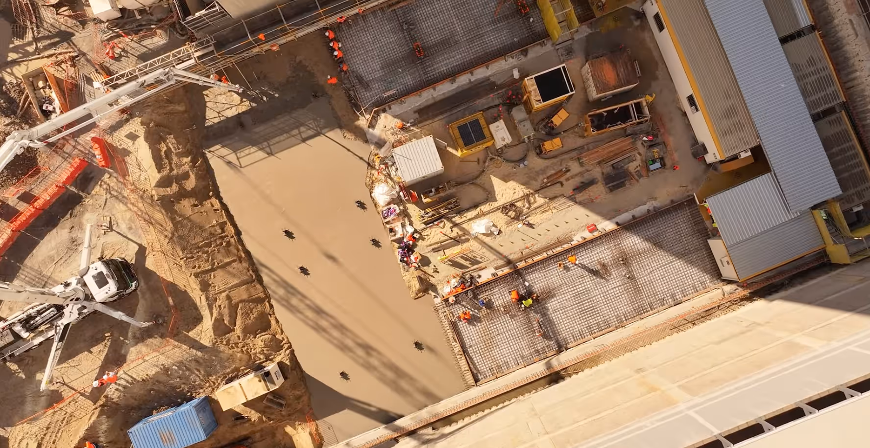 Grayscale aerial view of a large-scale urban construction site with multiple drilling rigs.