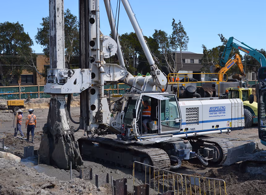Grayscale group portrait of construction workers standing in front of heavy machinery.
