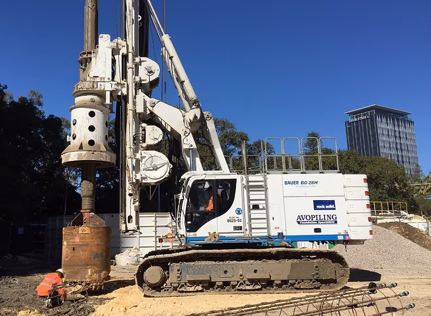 Grayscale group portrait of construction workers standing in front of heavy machinery.
