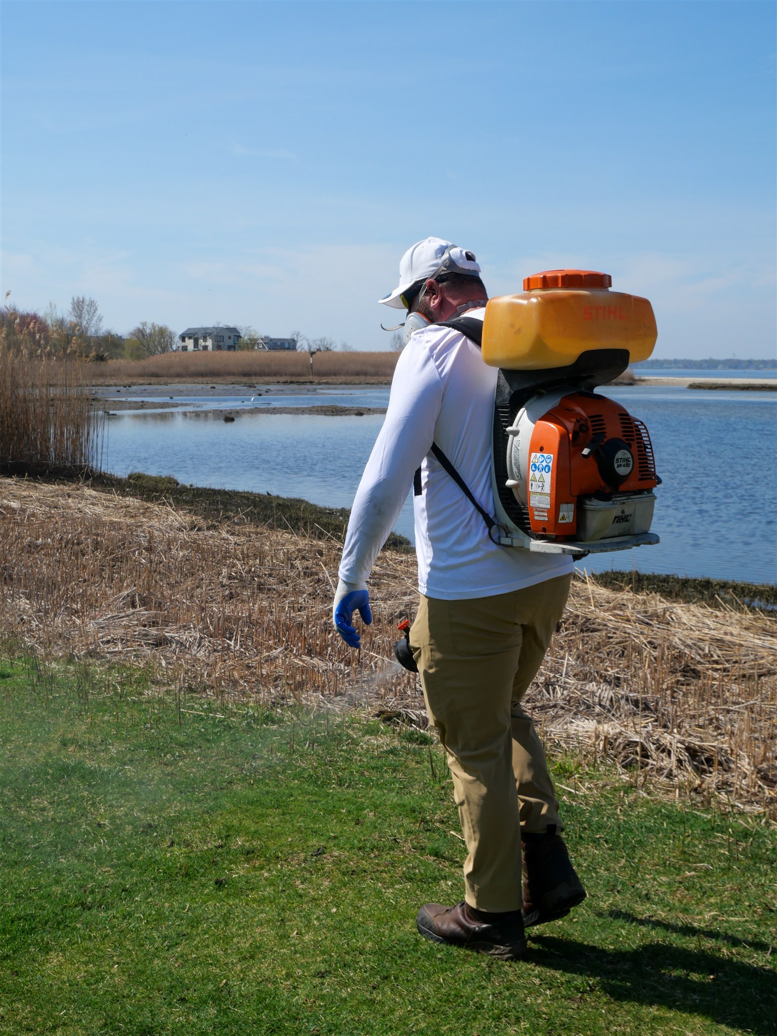 Technician treating the edge of a salt marsh, prime tick habitat in Massachusetts