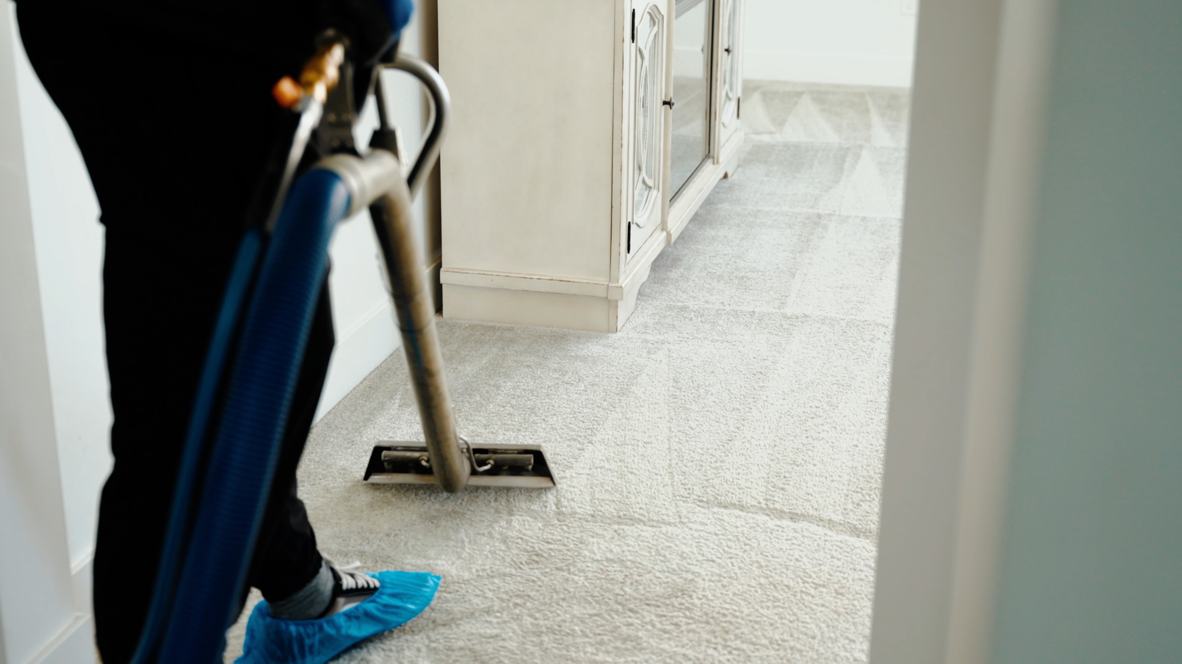 Technician deep cleaning beige carpet with a hot water extraction wand