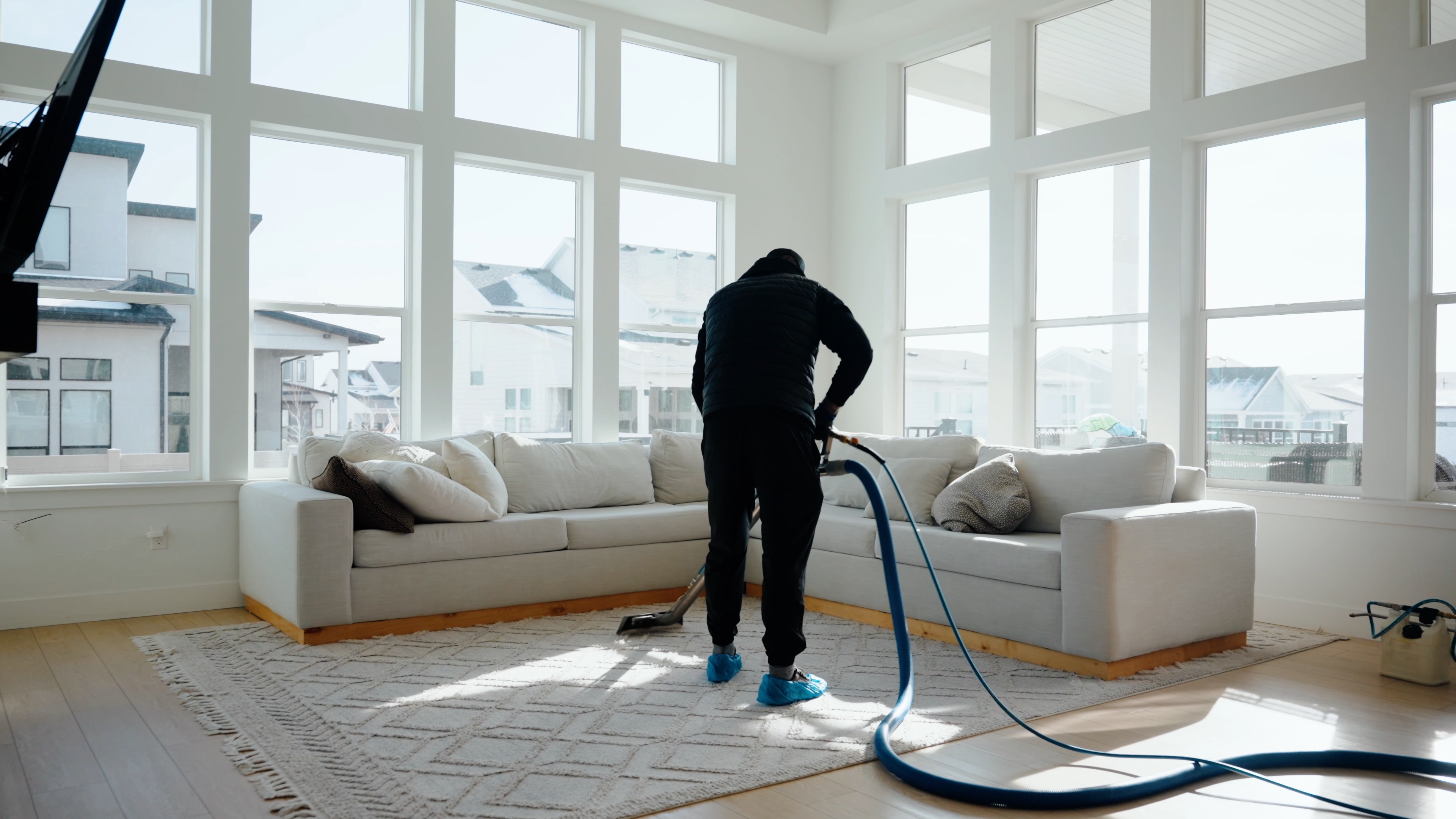 Technician cleaning a light area rug in a bright living room