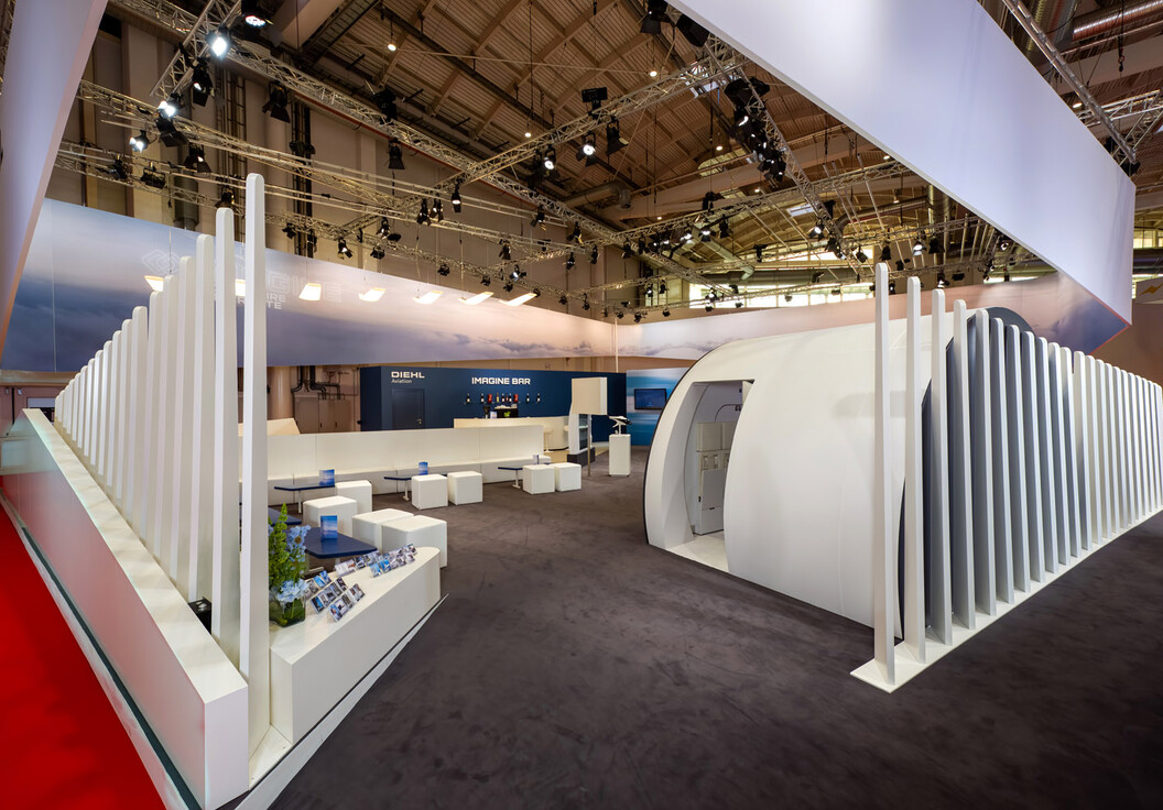 Geschwungene Deckenblende mit steigenden und fallenden Lamellen über der Lounge des Diehl-Aviation-Stands