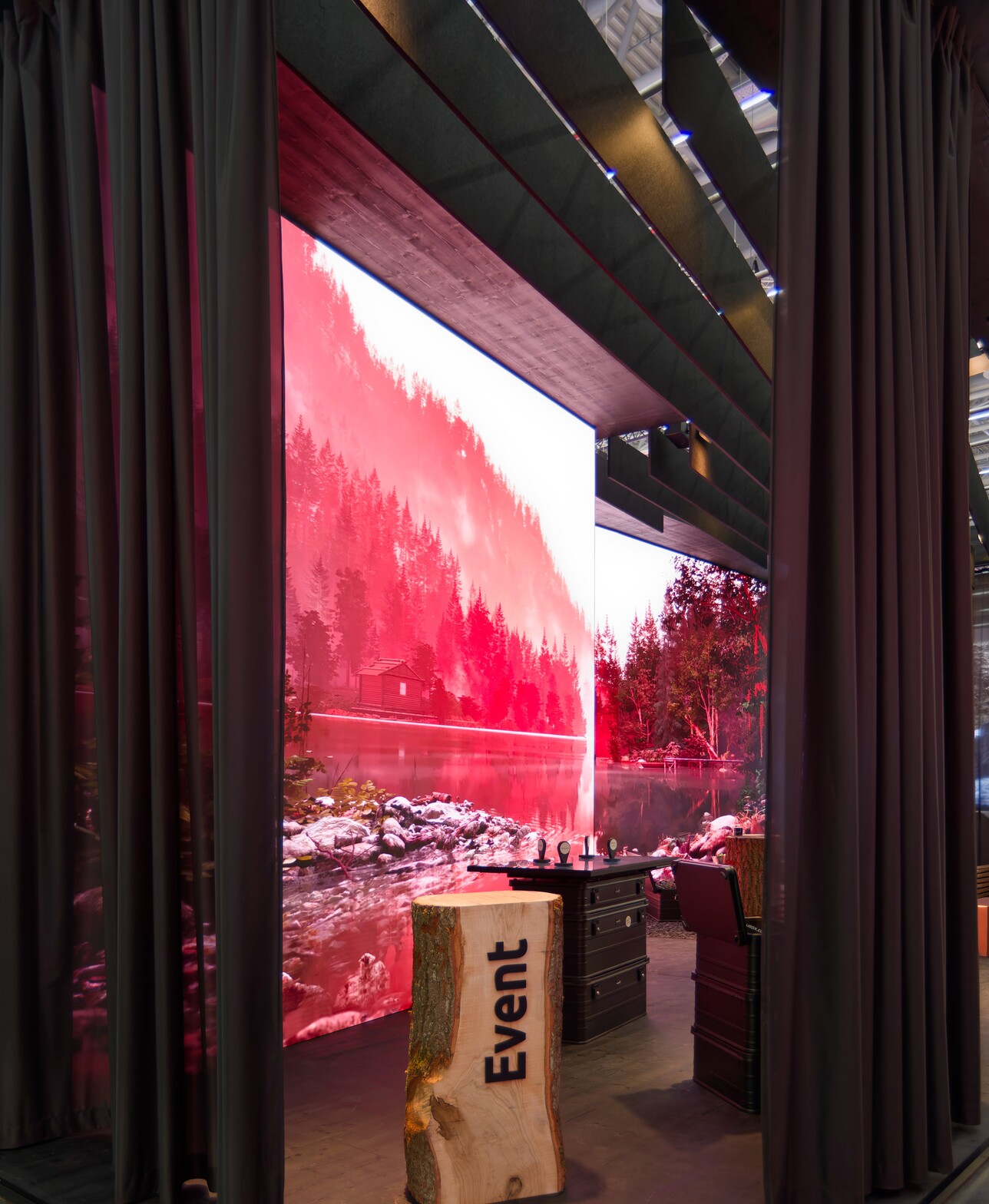 Durchblick durch die transparente Vorhangfassade auf die rot beleuchtete LED-Naturwand im Innenraum