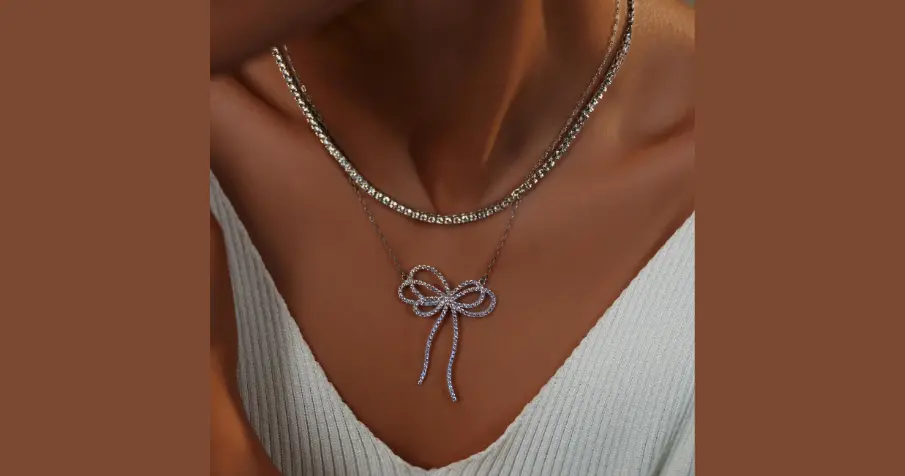 Woman wearing a gold chain necklace and holding another chain near her neck.