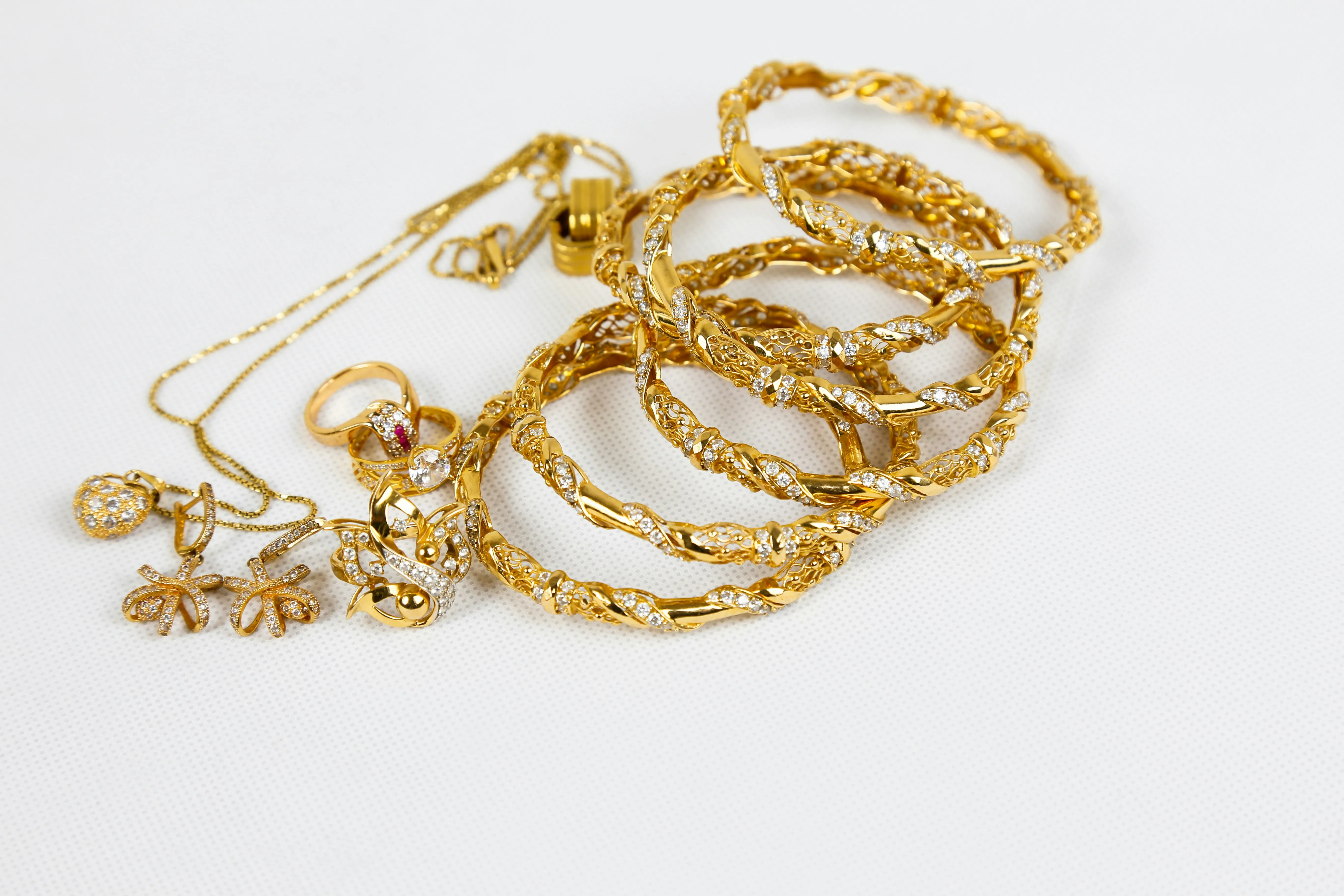 Woman wearing a gold chain necklace and holding another chain near her neck.