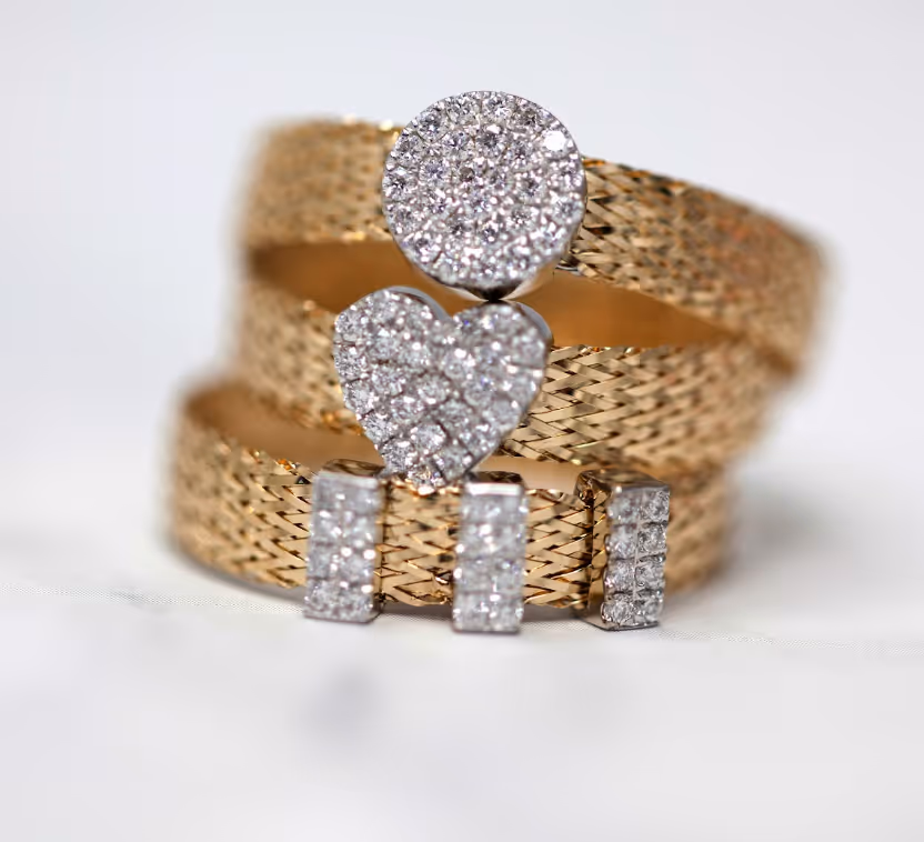 Close-up of a hand with delicate gold chain jewelry draped over fingers against a white background.