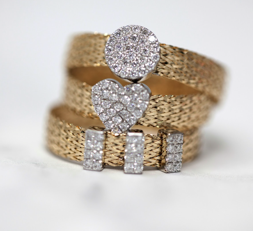 Close-up of a hand with delicate gold chain jewelry draped over fingers against a white background.