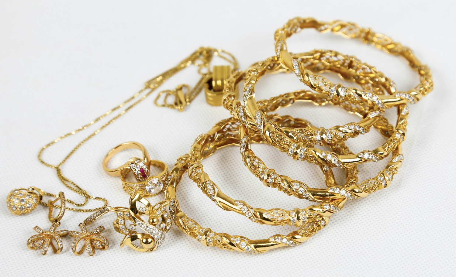 Woman wearing a gold chain necklace and holding another chain near her neck.