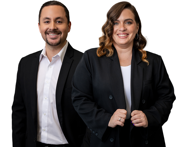 Smiling man and woman standing side by side, both wearing black blazers with white shirts underneath.