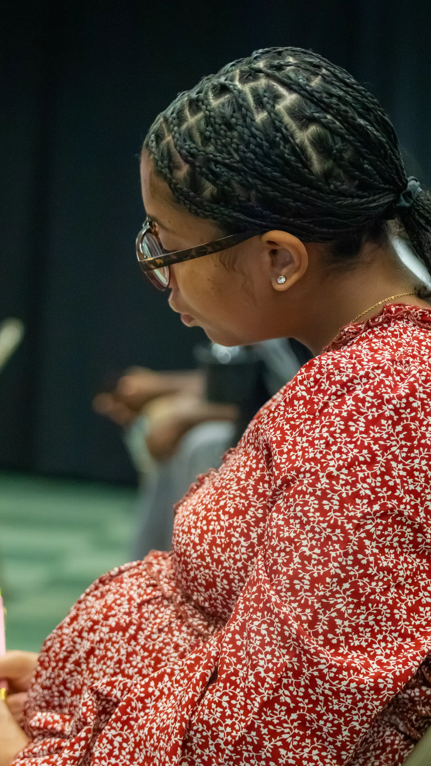 Woman in a red floral dress listening during a worship service at Restoration Church in Laurel, Maryland